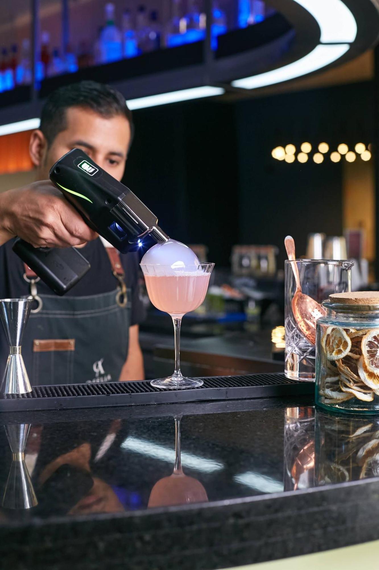 Pullman Santiago Vitacura エクステリア 写真 A bartender using a blowtorch to cook a cocktail